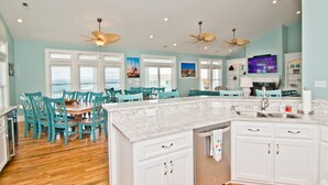 A spacious kitchen with white cabinets, a marble countertop, and teal chairs around a wooden table. - Pa's Place, Almost Oceanfront House in Emerald Isle, NC! (Emerald Isle)