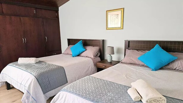 A hotel room with two beds, each with a headboard, a nightstand, a lamp, and a framed picture on the wall. - Suite moderna 301. La Mejor Ubicación

 (Quito)