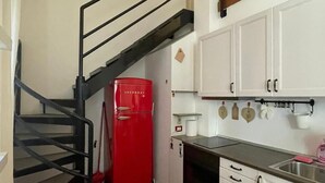 Una cucina con mobili bianchi, una moka rossa e un lavello in acciaio inossidabile.
