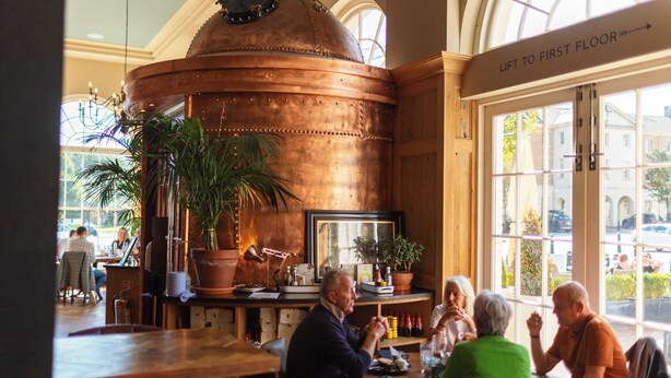 A restaurant with a large copper dome, wooden tables, and potted plants. - The Duchess of Cornwall Inn (Dorchester)