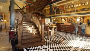 A bar area with a checkered floor, wooden staircase, and bar stools. - The Duchess of Cornwall Inn (Dorchester)