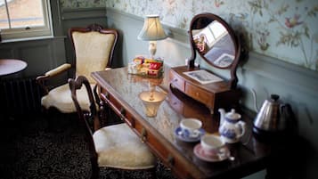Una habitación con un escritorio de madera, dos sillas, una lámpara, un espejo y un radiador.