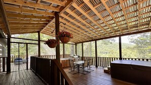Um deck de madeira com corrimão, uma mesa e cestos de flores pendurados.