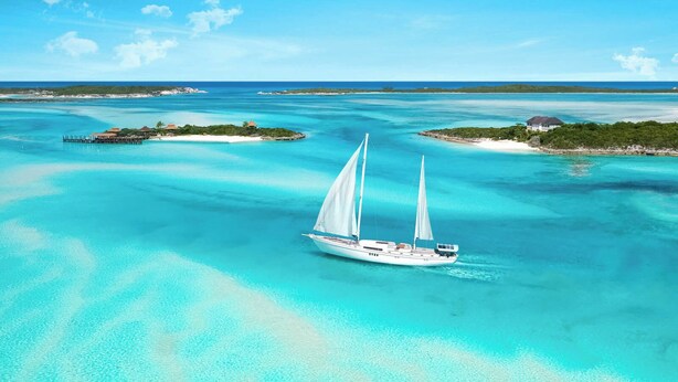 Un grand yacht navigue sur une mer turquoise sous un ciel dégagé.