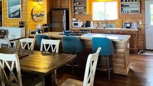 L’intérieur d’une cabane en bois comprend un coin repas, une cuisine et un ventilateur de plafond.