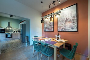 Een moderne keuken met een eethoek, met een granieten aanrecht, roestvrijstalen apparatuur en een houten eettafel met teal stoelen.