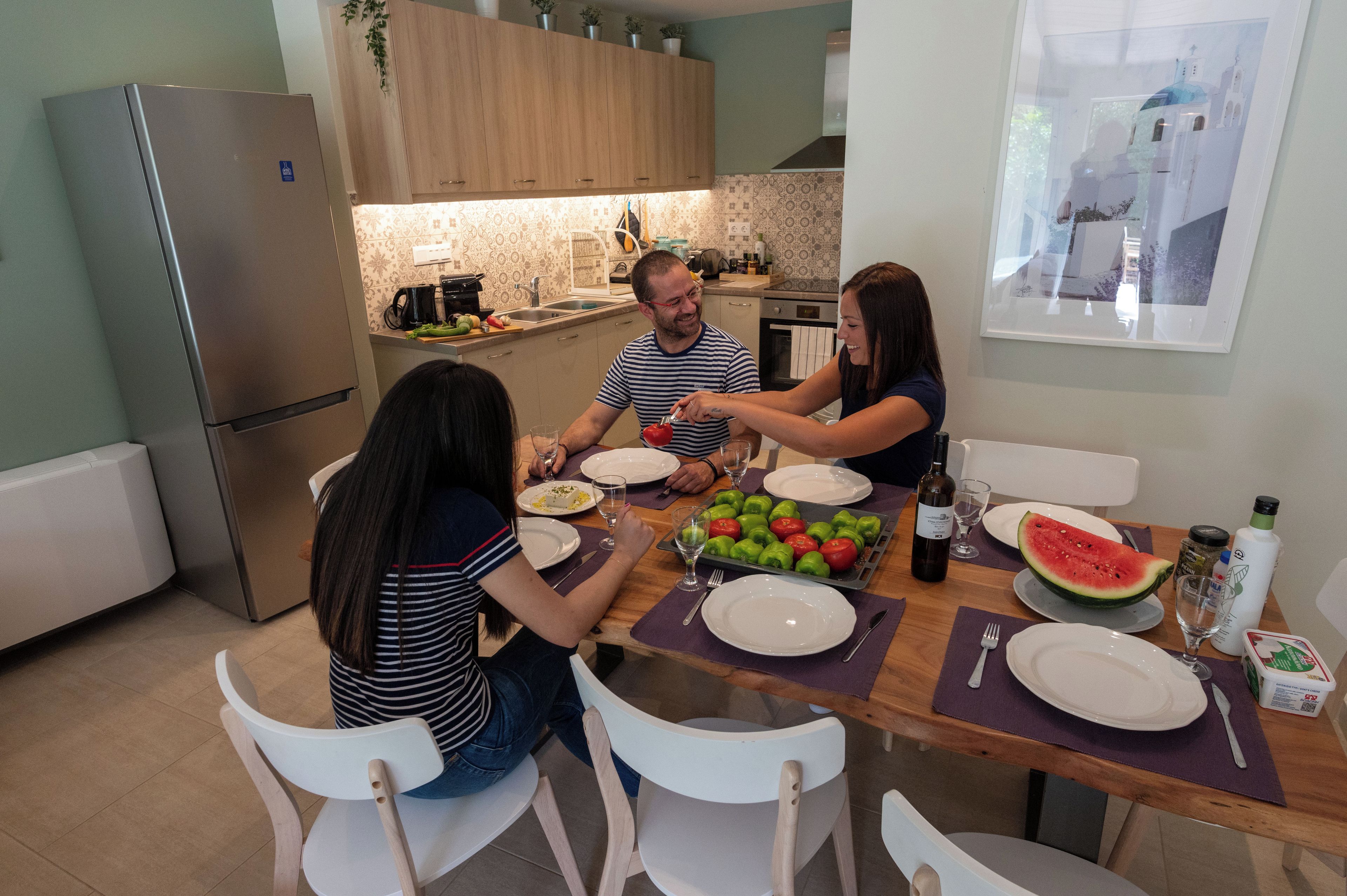 A dining area with a wooden table, chairs, and a kitchen in the background.
