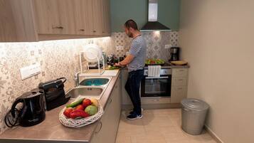 A kitchen with wooden cabinets, a sink, a coffee maker, and a trash can.