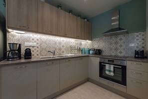 Een keuken met houten kastjes, een roestvrijstalen afzuigkap en een decoratieve spatwand.