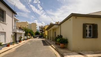 A narrow street lined with residential buildings, some with balconies and potted plants.