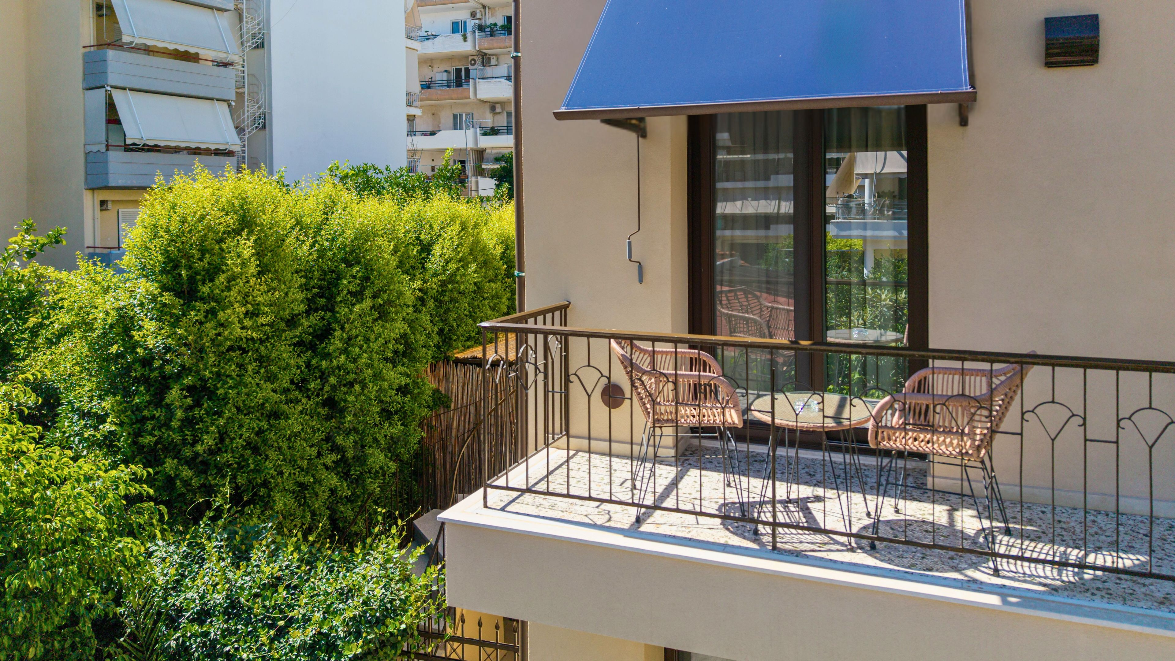 Ein Balkon mit Korbstühlen und einem Tisch, umgeben von dichtem Grün.