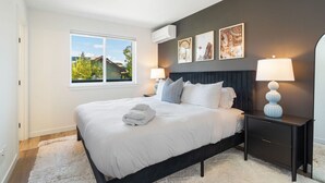 Un dormitorio con una cama grande, dos lámparas de noche, una ventana con vistas y obras de arte en la pared.