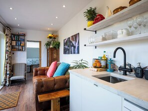 Une cuisine équipée d’un évier, d’un banc en bois, d’une bibliothèque et d’un coin repas comprenant un canapé et une chaise.