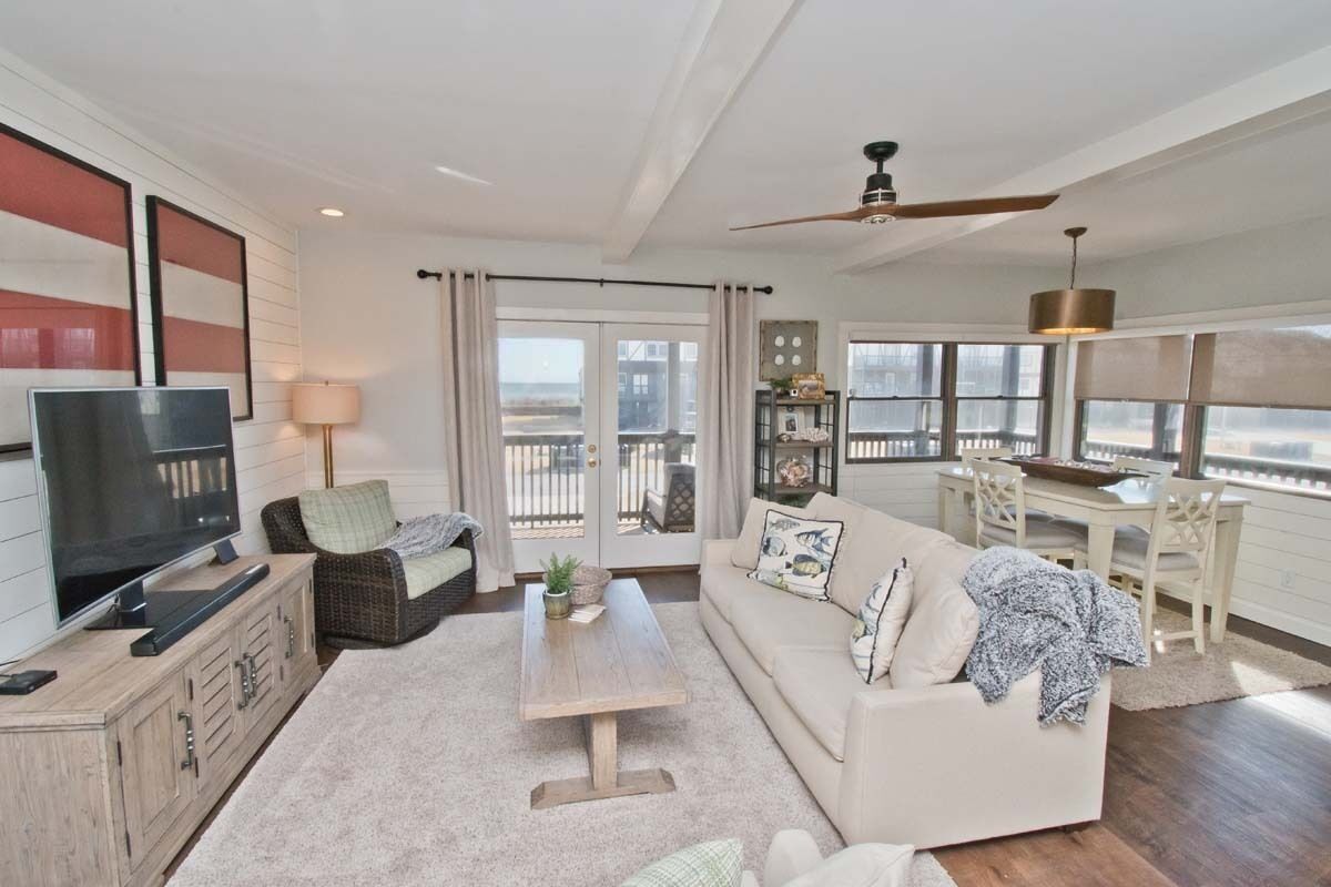 A spacious living room with a television, sofa, and coffee table. There is a balcony with a view of the city.