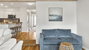 Un salon moderne avec un canapé gris, un divan blanc et une table basse en bois.