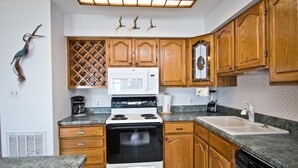 Una cocina con armarios de madera, una estufa blanca, un microondas y un fregadero.