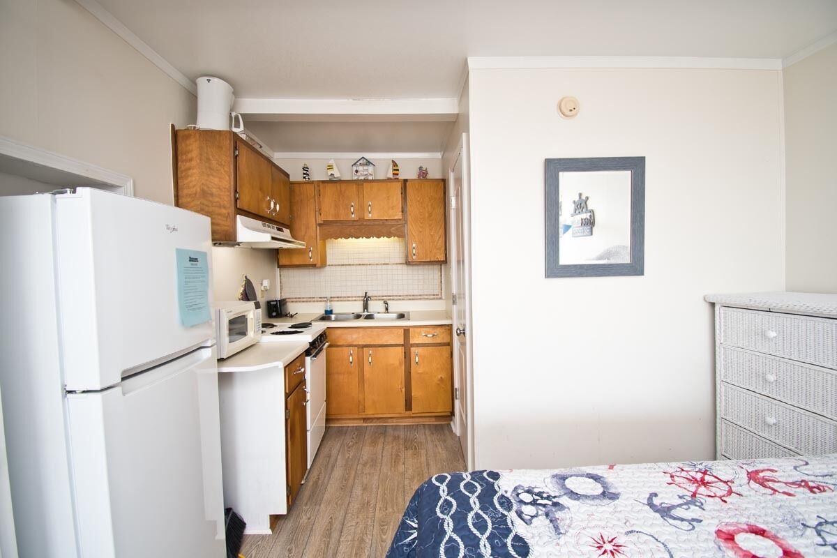 A compact kitchen with wooden cabinets, a white refrigerator, and a microwave.