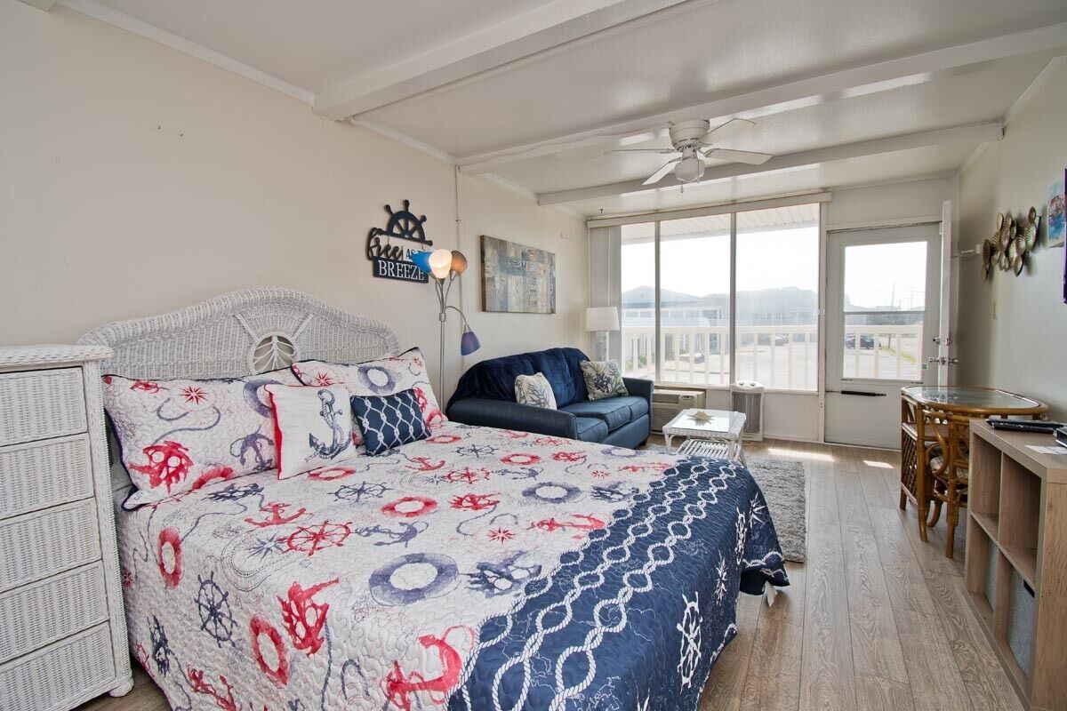 A bedroom with a bed, a sofa, a desk, and a window with a view.
