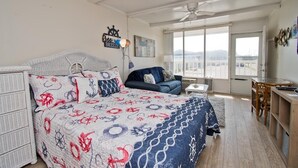 Ein Schlafzimmer mit Bett, Sofa, Schreibtisch und einem Fenster mit Blick.