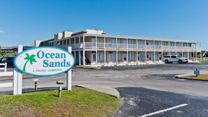 Ein zweistöckiges Gebäude mit einem Schild, auf dem „Ocean Sands – eine private Wohnanlage“ steht.
