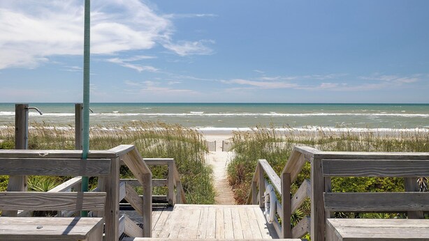 A wooden boardwalk leading to a beach with a clear view of the ocean. - Ocean Terrace #2, Oceanfront Condo in Pine Knoll Shores, NC! (Pine Knoll Shores)