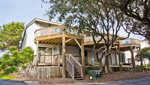 A two-story building with a wooden deck and a staircase leading to the upper level. - Oceans #11, Oceanside Condo in Pine Knoll Shores, NC! (Pine Knoll Shores)