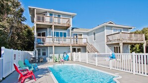 Une maison à deux étages avec une piscine, une terrasse clôturée et un espace salon extérieur.