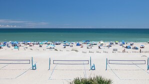 A beach with multiple umbrellas and tents, a volleyball net, and a clear view of the ocean. - Palm Cottage I At The Grove, Oceanfront House in Atlantic Beach, NC! (Atlantic Beach)