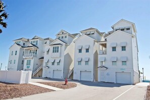 A row of white beachfront condominiums with multiple garage doors and balconies.