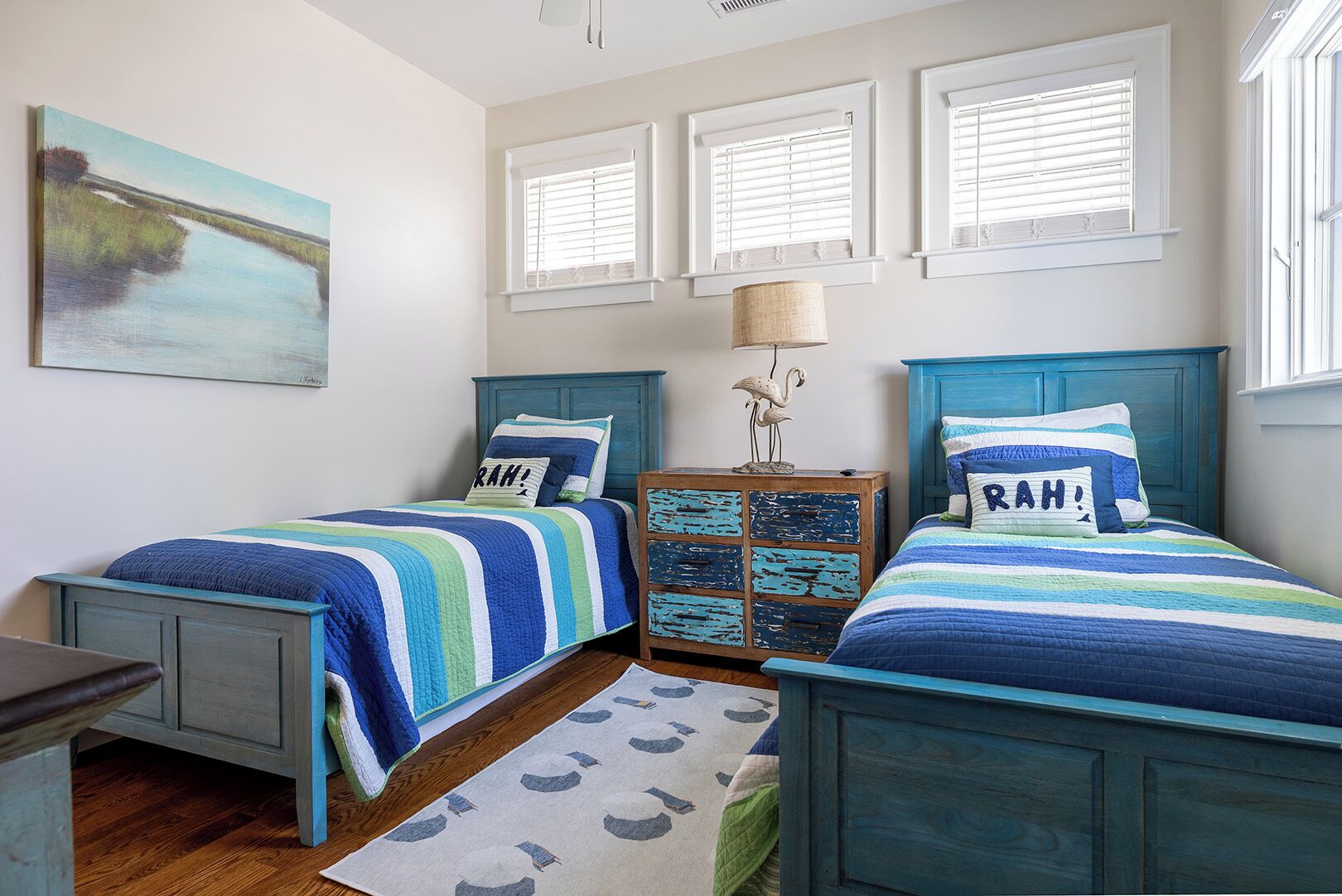 A bedroom with two beds, a nightstand, a lamp, and a painting.