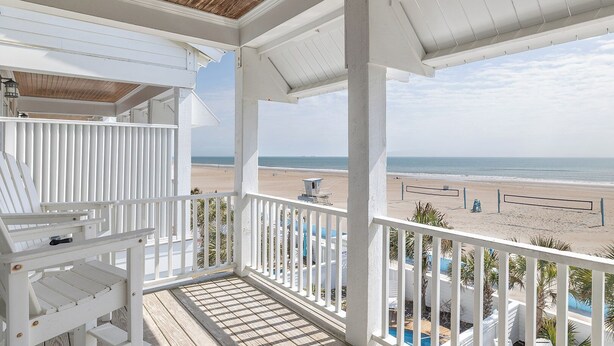Un balcon fermé offrant une vue sur une plage et un poste de surveillance des sauveteurs.