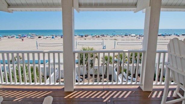 A beach view from a covered porch with a wooden deck and white railings. - Palm Cottage III At The Grove, Oceanfront House in Atlantic Beach, NC! (Atlantic Beach)
