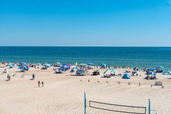 A beach with umbrellas, people, and a lifeguard tower.