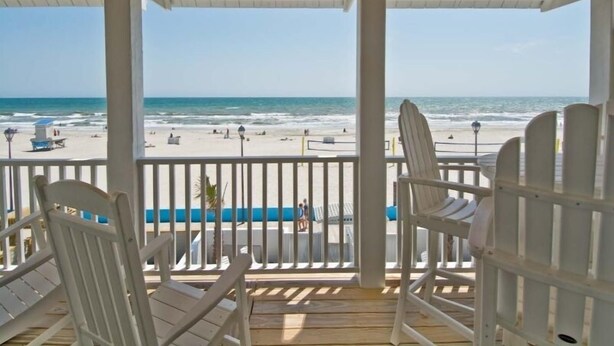 Un espace extérieur abrité, doté de chaises blanches et offrant une vue sur la plage.