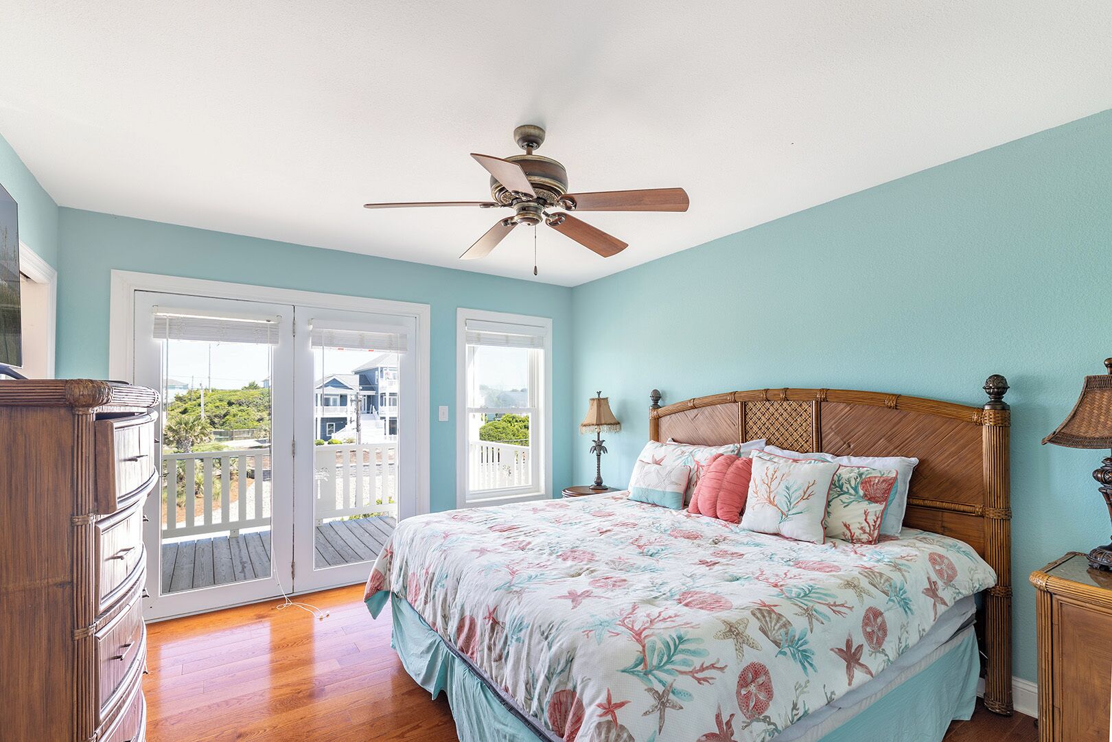 A bedroom with a bed, a ceiling fan, a nightstand, and a dresser.