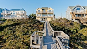 Une propriété située en bord de mer, avec une promenade en bois menant à un immeuble à plusieurs étages doté de balcons.