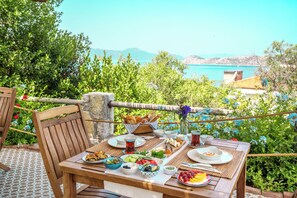 A wooden table set with various dishes and drinks, overlooking a scenic view of a body of water and greenery. - Bademli Bahçe Otel (Marmaris)