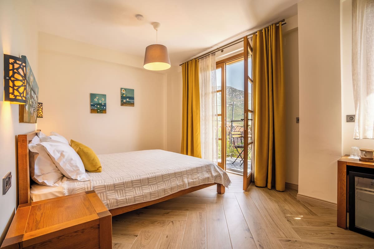 A bedroom with a bed, wooden nightstand, and a small table with a cup.
