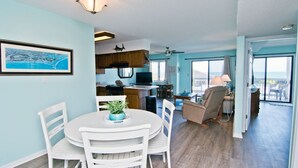 Un vaste espace de vie comprenant un coin repas avec table et chaises, une cuisine dotée de meubles en bois et une grande fenêtre offrant une vue dégagée.