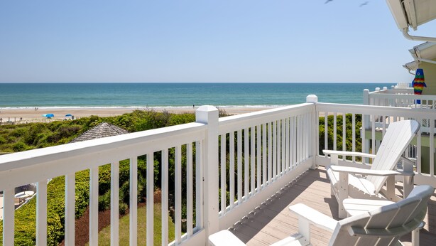 A deck with white railings, two Adirondack chairs, and a view of the beach and ocean. - Pebble Beach A-304, Oceanfront Condo in Emerald Isle, NC! (Emerald Isle)