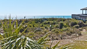 A coastal walkway with a wooden deck leading to a gazebo overlooking the sea.