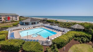 A swimming pool with lounge chairs, a gazebo, and a view of the beach.