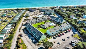 An aerial view of a coastal hotel with multiple buildings, a parking lot, and a beach in the background. - Pebble Beach D-202, Oceanfront Condo in Emerald Isle, NC! (Emerald Isle)