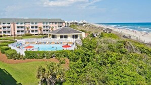 A hotel with a swimming pool, beach view, and multiple balconies. - Pebble Beach 1-110, Oceanside Condo in Emerald Isle, NC! (Emerald Isle)