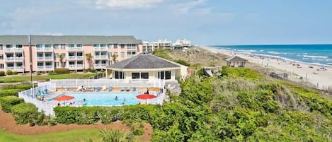 A hotel with a swimming pool, beach view, and multiple balconies.