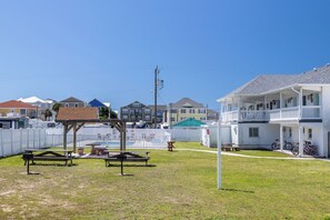 A residential area with houses, a fenced yard, picnic tables, and bicycles.