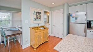 A kitchen with a wooden cabinet, a refrigerator, and a dining area with a table and chairs.