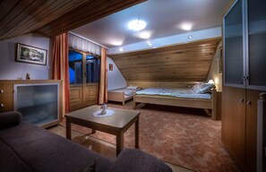 Cozy cabin room with a wooden bed, sofa, and TV, perfect for a relaxing stay.
