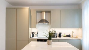 A modern kitchen with a central island, built-in appliances, and a sleek design. - The Battersea Scenery - Elegant 2bdr Flat (London)