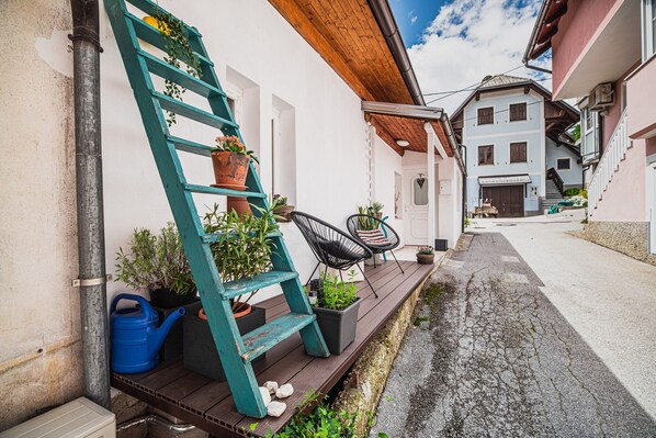 A wooden deck with a teal ladder, potted plants, and outdoor furniture.